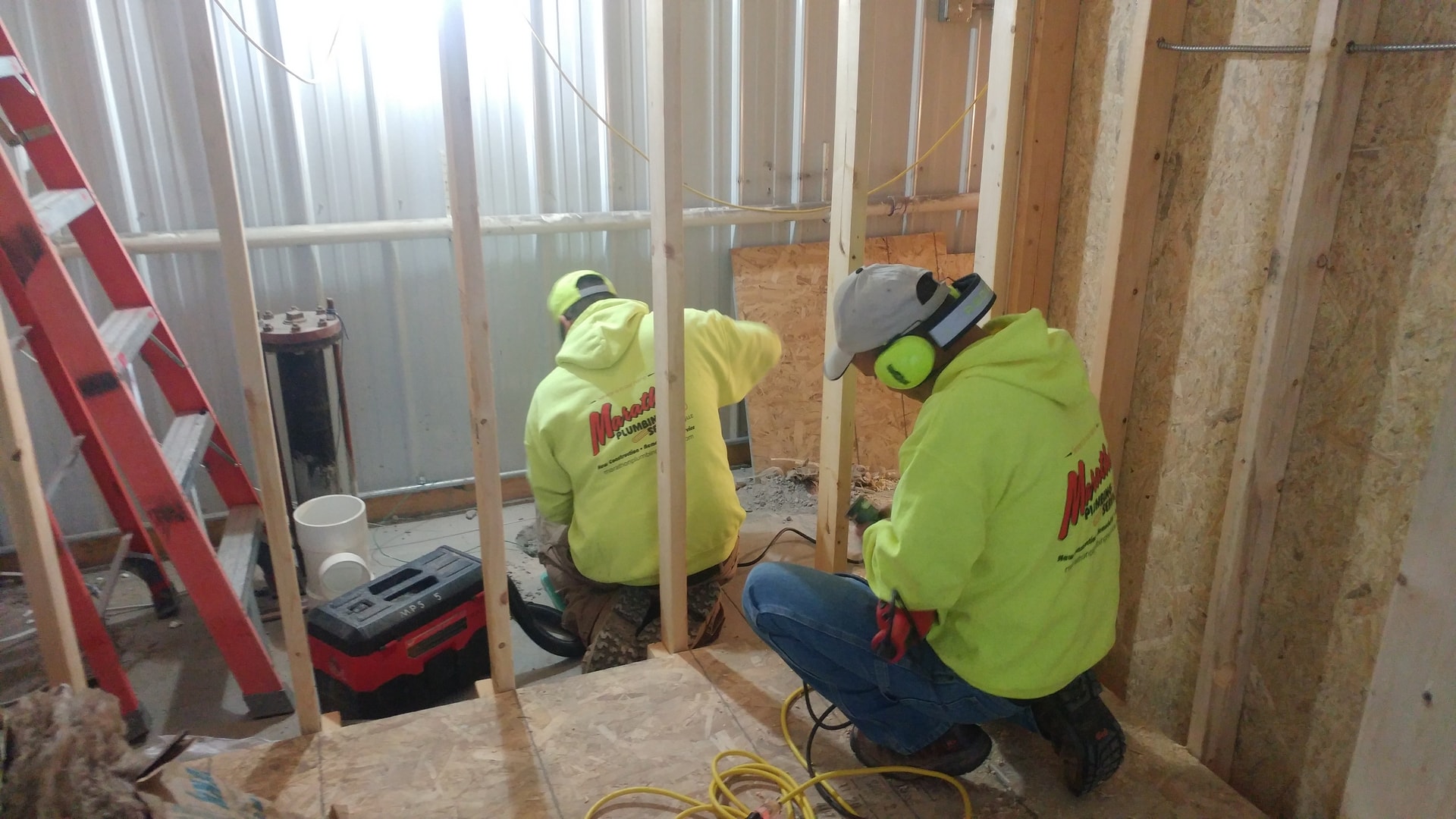 Two MPS crew members in safety gear working on new construction plumbing