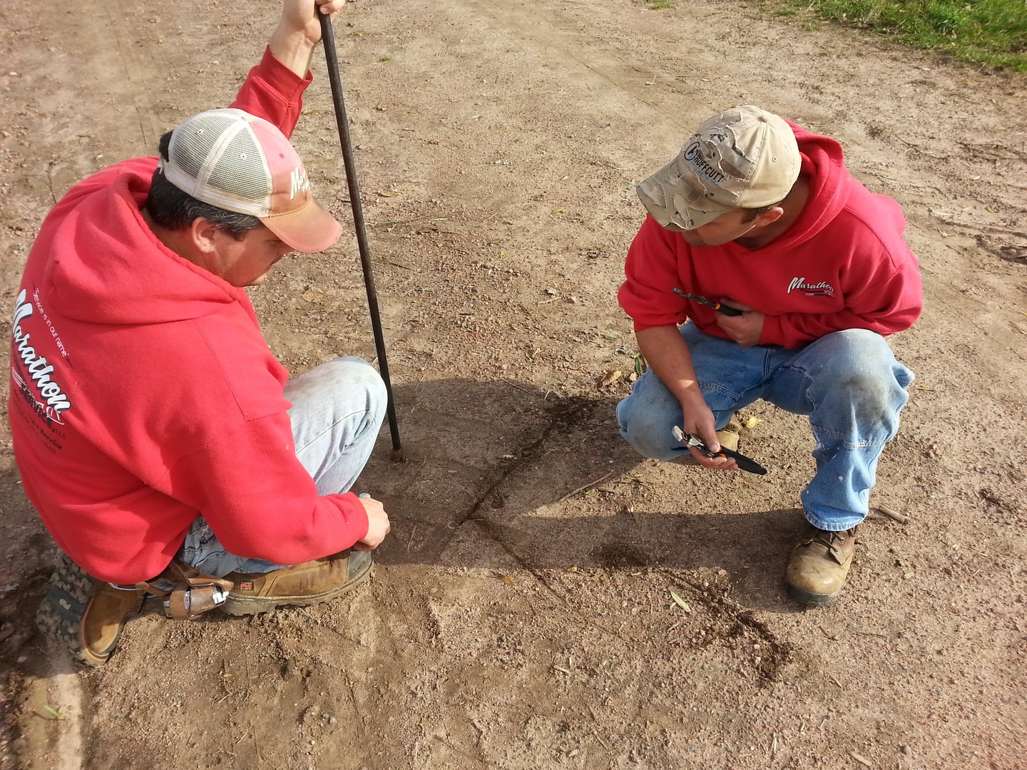 Two MPS crew members in red sweatshirts working outdoors on a job site