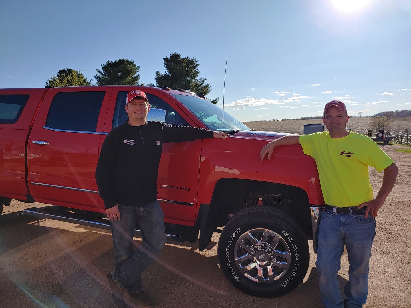 Two Marathon Plumbing Service owners standing with their red work truck
